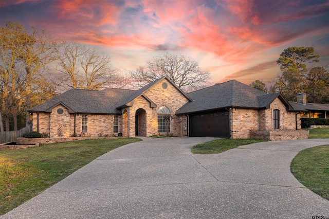 french country inspired facade with an attached garage, brick siding, concrete driveway, roof with shingles, and a front lawn