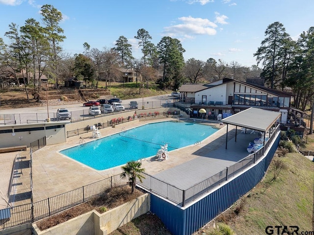 community pool with a patio area and fence