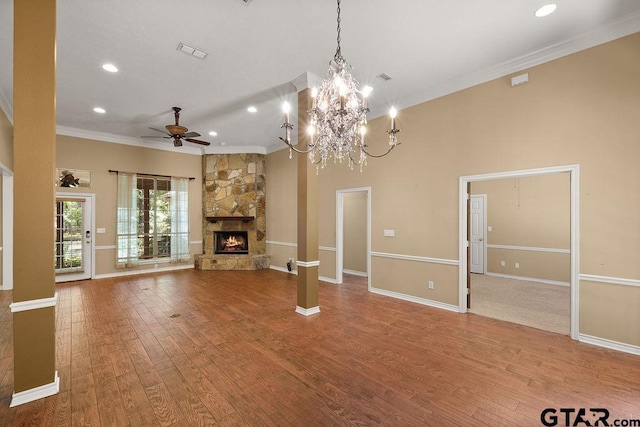 unfurnished living room featuring crown molding, wood finished floors, a stone fireplace, ceiling fan with notable chandelier, and visible vents