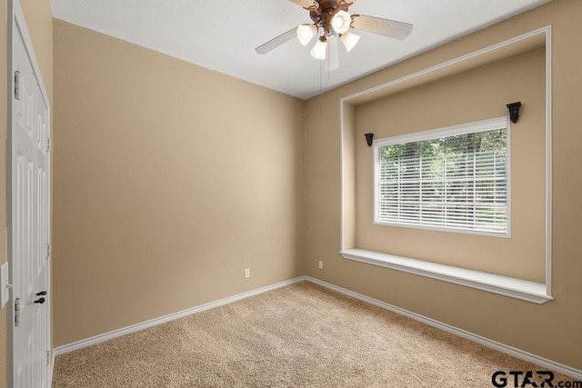 carpeted empty room featuring a ceiling fan and baseboards