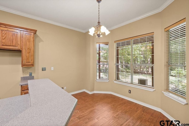 unfurnished dining area featuring wood finished floors, ornamental molding, a notable chandelier, and plenty of natural light