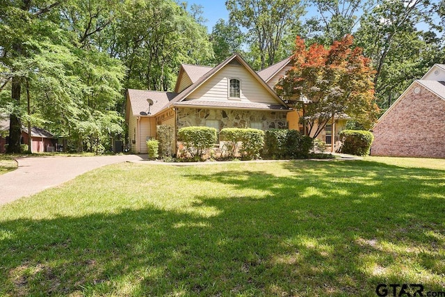 view of front of property with concrete driveway, a front lawn, stone siding, and a garage