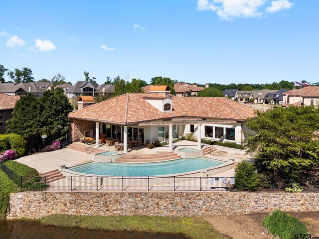 outdoor pool with a residential view, a patio area, fence, and an in ground hot tub