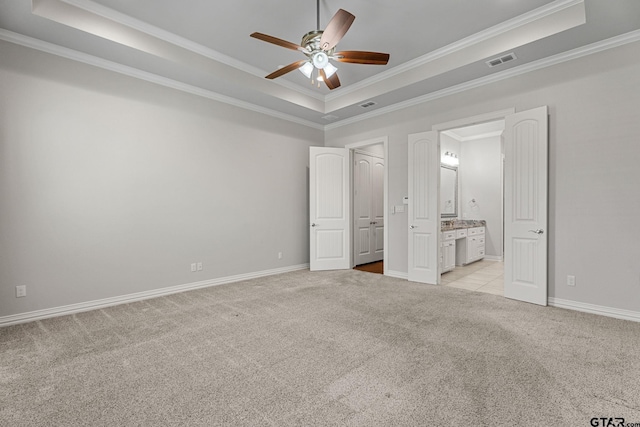 unfurnished bedroom featuring light carpet, visible vents, a tray ceiling, and crown molding