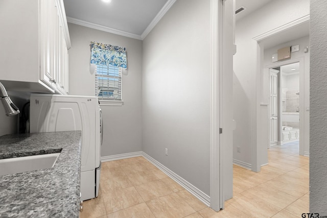 clothes washing area featuring baseboards, a sink, crown molding, cabinet space, and washing machine and clothes dryer