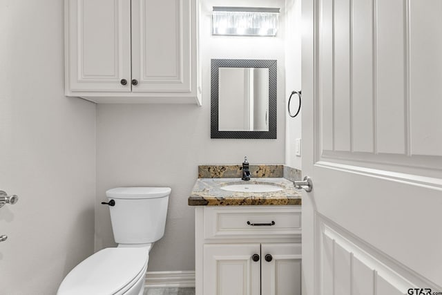 bathroom featuring toilet, vanity, and baseboards