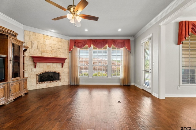 unfurnished living room featuring crown molding, ceiling fan, a stone fireplace, wood-type flooring, and baseboards