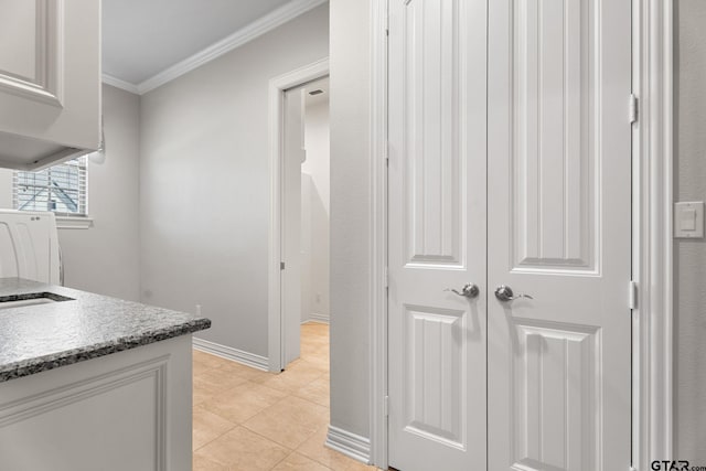 interior space with baseboards, ornamental molding, light stone countertops, washer / dryer, and light tile patterned flooring