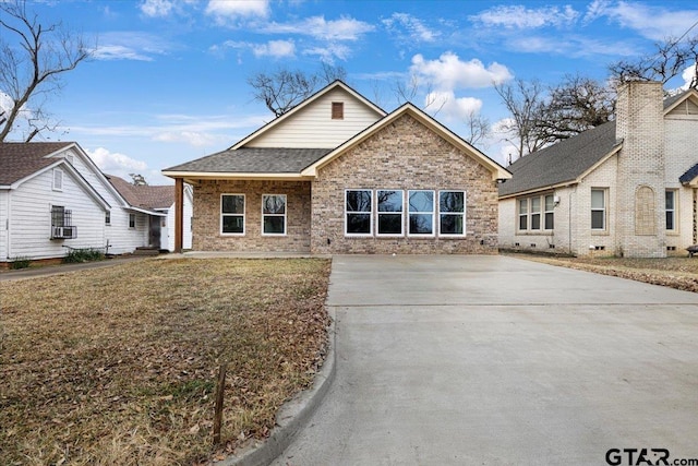 view of front of home with cooling unit, brick siding, a shingled roof, driveway, and a front yard