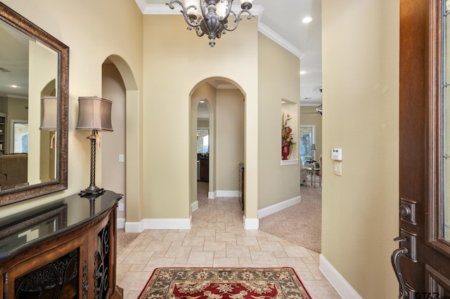 entryway with ceiling fan with notable chandelier, light colored carpet, and ornamental molding