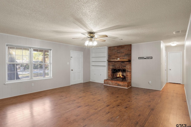 unfurnished living room with hardwood / wood-style flooring, a textured ceiling, and a brick fireplace