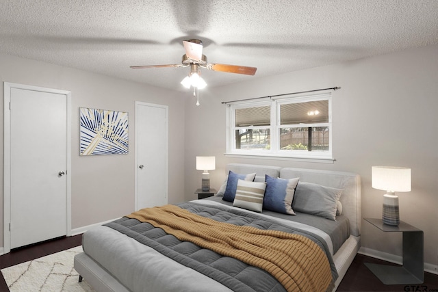 bedroom with ceiling fan, dark hardwood / wood-style flooring, and a textured ceiling