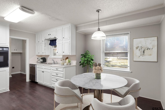 dining area with sink, dark hardwood / wood-style floors, wood walls, a textured ceiling, and ornamental molding