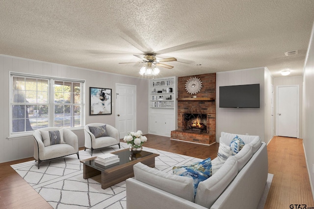 living room with a textured ceiling, light hardwood / wood-style flooring, and ceiling fan