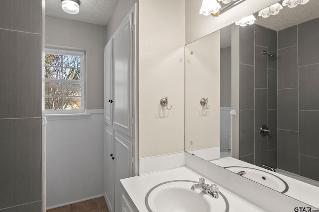 bathroom featuring tile patterned floors, sink, a textured ceiling, and a tile shower