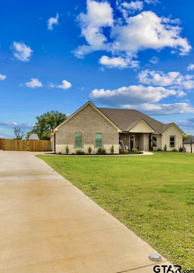 view of front of house featuring brick siding, fence, and a front lawn