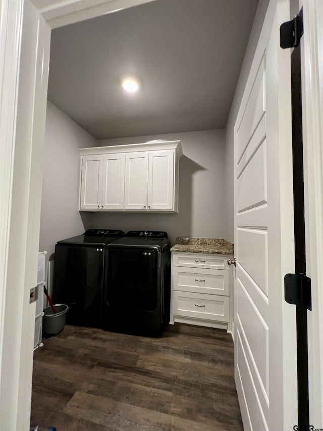 washroom featuring cabinets, washing machine and clothes dryer, and dark hardwood / wood-style flooring