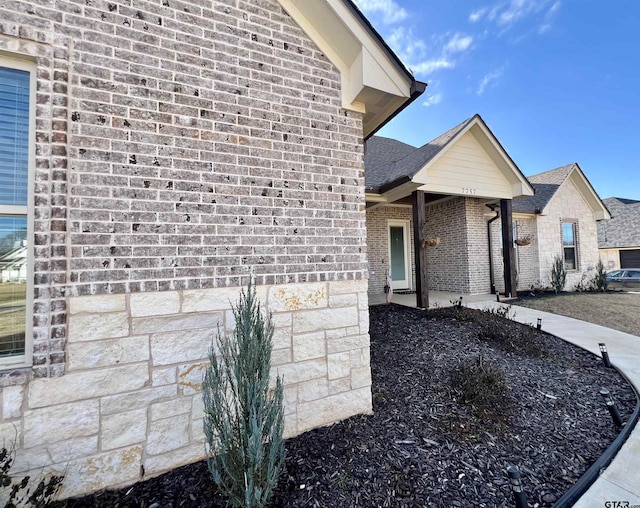 exterior space with a shingled roof and brick siding