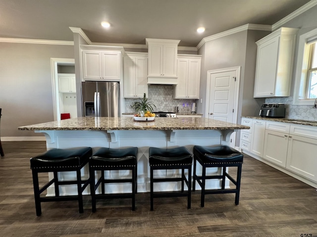 kitchen with stainless steel fridge, a center island, and white cabinets