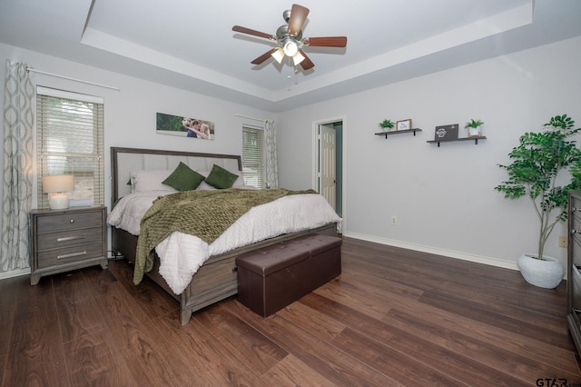 bedroom featuring a tray ceiling, dark wood-type flooring, and ceiling fan