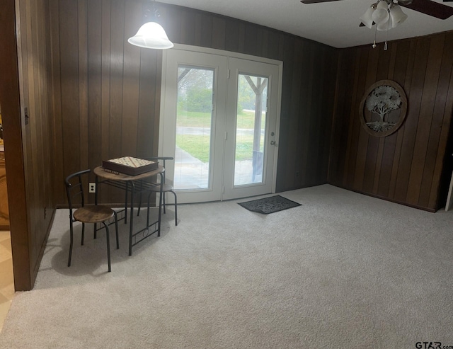 doorway with wooden walls, light carpet, and plenty of natural light