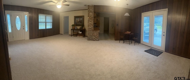 carpeted entryway with wooden walls and ceiling fan