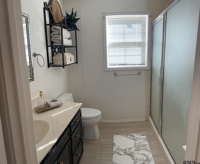 bathroom with a shower with door, vanity, and toilet