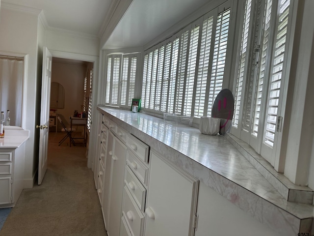 kitchen featuring white cabinets, light carpet, and crown molding