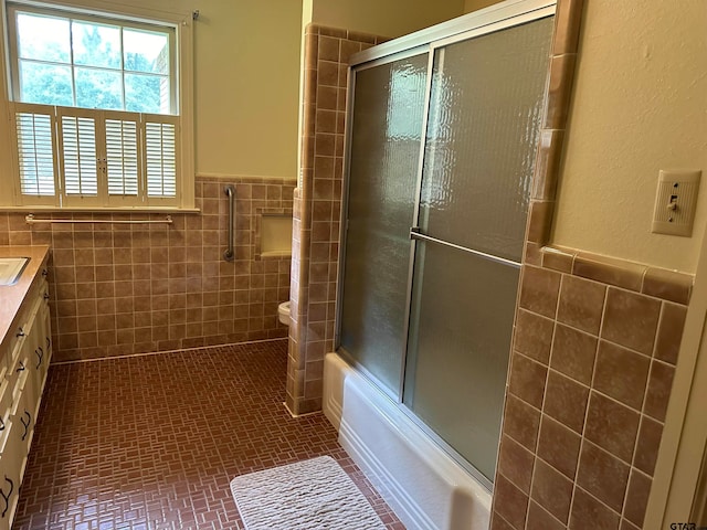 full bathroom featuring tile walls, vanity, toilet, and enclosed tub / shower combo