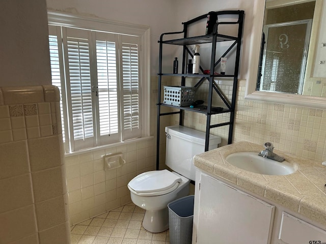 bathroom with vanity, tile patterned floors, toilet, and tile walls