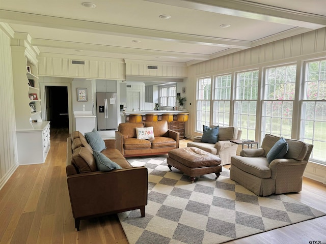 living room with a wealth of natural light, light hardwood / wood-style floors, and crown molding