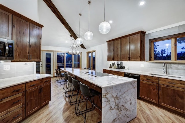 kitchen featuring a center island, sink, light stone counters, pendant lighting, and black appliances