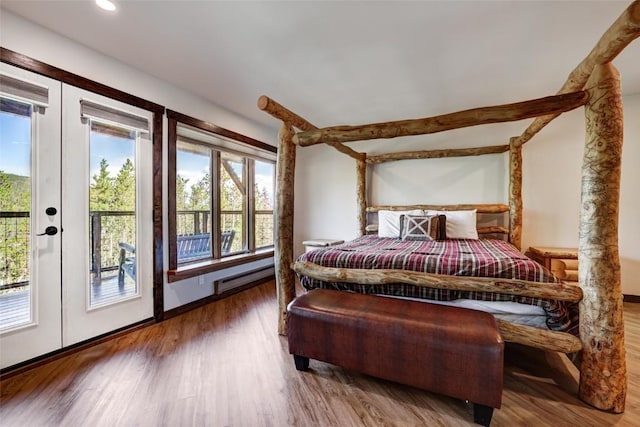 bedroom with access to exterior, french doors, a baseboard heating unit, and hardwood / wood-style floors