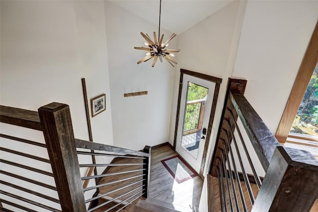 stairs with a notable chandelier, lofted ceiling, and hardwood / wood-style flooring