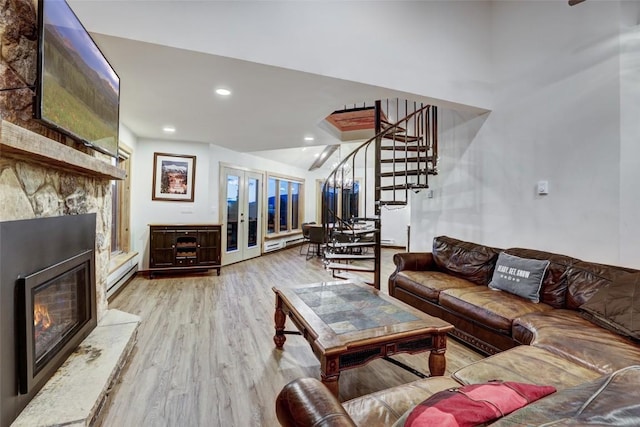 living room with lofted ceiling, a baseboard heating unit, french doors, light wood-type flooring, and a fireplace