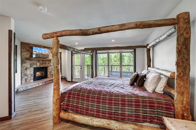 bedroom featuring access to exterior, wood-type flooring, and a fireplace