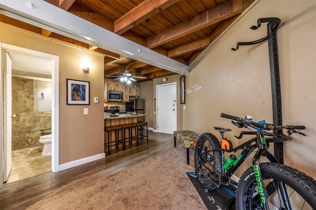 workout room with ceiling fan, carpet floors, and wood ceiling