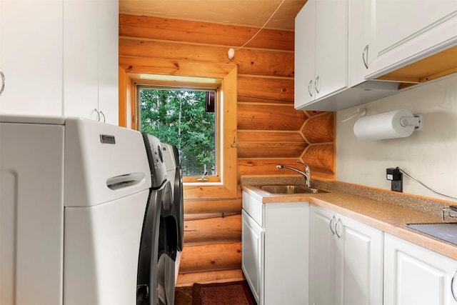 kitchen featuring white cabinetry, sink, and log walls