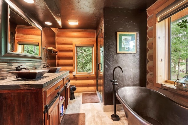 bathroom with a washtub, vanity, plenty of natural light, and log walls