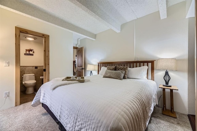 carpeted bedroom with beam ceiling, connected bathroom, and a textured ceiling