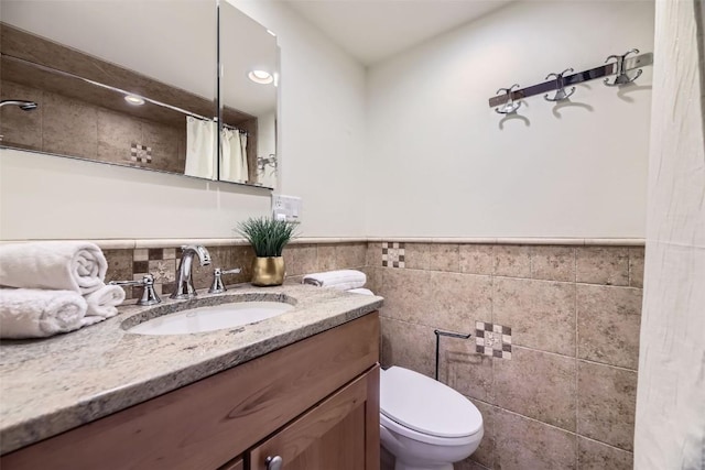 bathroom with a shower with shower curtain, vanity, toilet, and tile walls