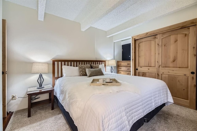 bedroom featuring beam ceiling, light colored carpet, and a textured ceiling