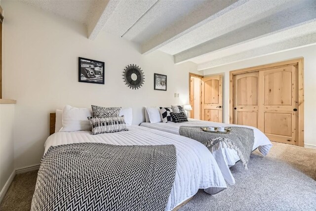 bedroom featuring beamed ceiling, a textured ceiling, and carpet flooring