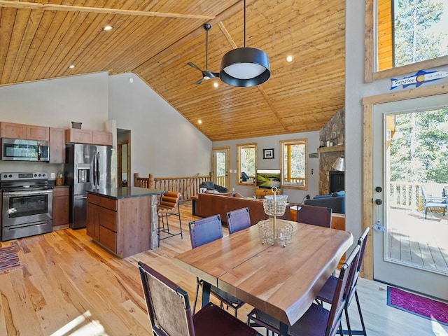 dining space with high vaulted ceiling, light wood-type flooring, wood ceiling, and a stone fireplace