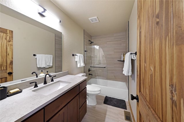 full bathroom featuring toilet, tiled shower / bath combo, a textured ceiling, and vanity