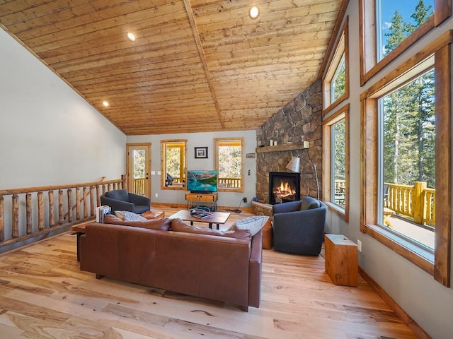 living room with lofted ceiling, light hardwood / wood-style floors, wood ceiling, and a stone fireplace