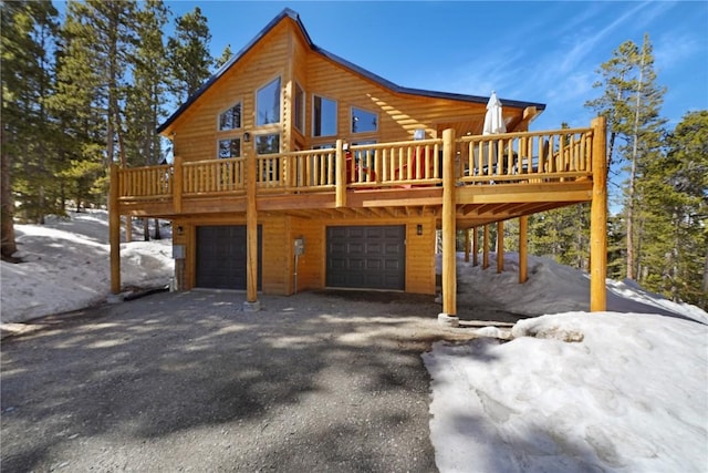 snow covered rear of property with a deck and a garage