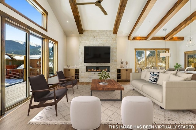 living room featuring a mountain view, beam ceiling, a fireplace, and ceiling fan