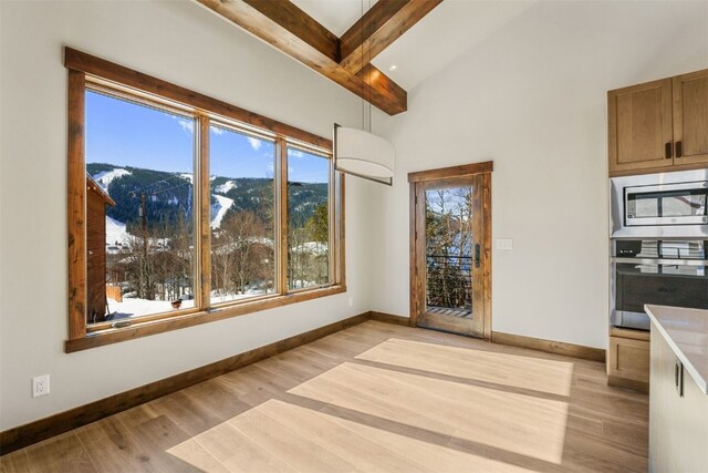 interior space with a mountain view, beam ceiling, and light hardwood / wood-style floors