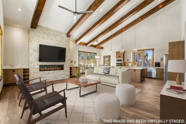 living room with beamed ceiling, a wealth of natural light, a fireplace, and high vaulted ceiling